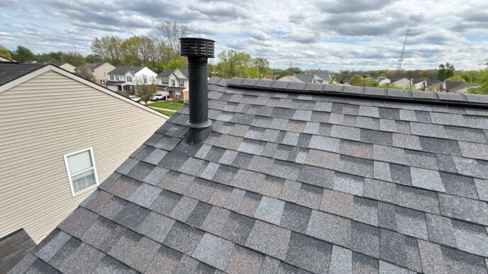 Newly shingled roof with a vent pipe under a cloudy sky