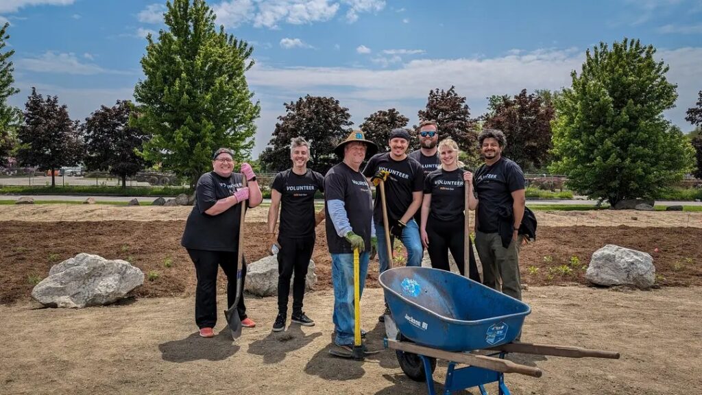 RoofAdvisor Gives Back: Volunteers pose with tools and a wheelbarrow in a landscaping project. Giving back to the community,