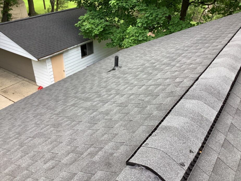 Westland Roof Replacement: Gray asphalt shingles on a residential roof, showcasing a recent roof replacement with a clean ridge vent and backyard view.