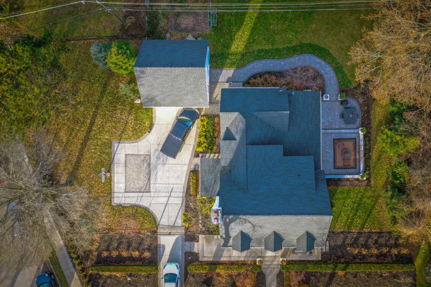 Aerial view of a house with a gray roof, driveway, and landscaped yard.