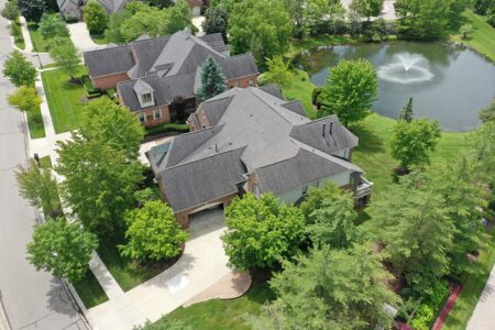 Aerial view of Claremont buildings, a current community project, featuring angled photos of houses, green trees, and a pond with a fountain.