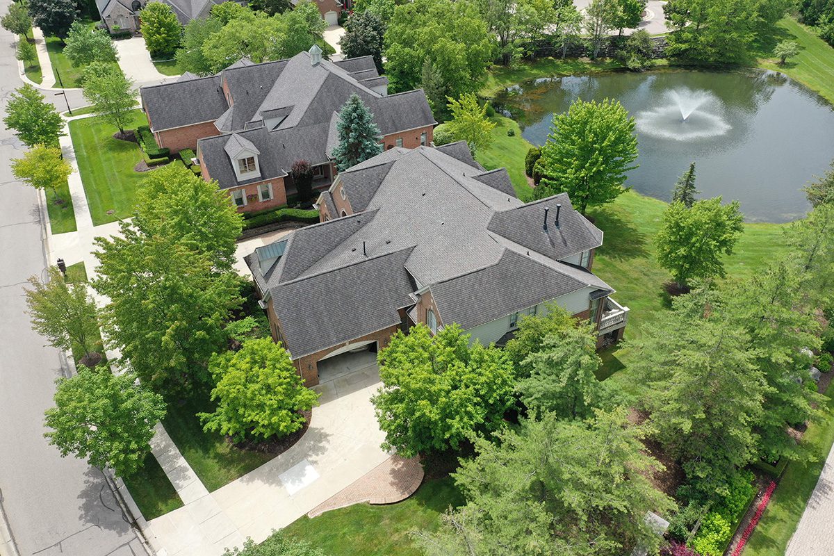 Aerial view of Claremont buildings, a current community project, featuring angled photos of houses, green trees, and a pond with a fountain.