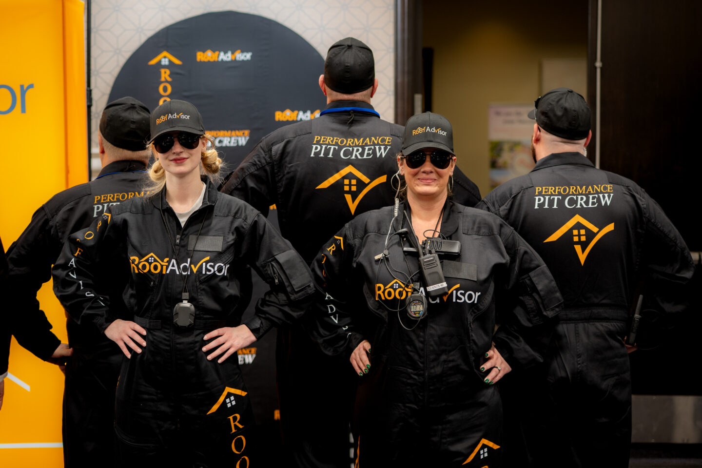 RoofAdvisor's Performance Pit Crew, CAI2026015, showcases team members in branded jumpsuits and hats, highlighting the roofing company's presence and expertise.