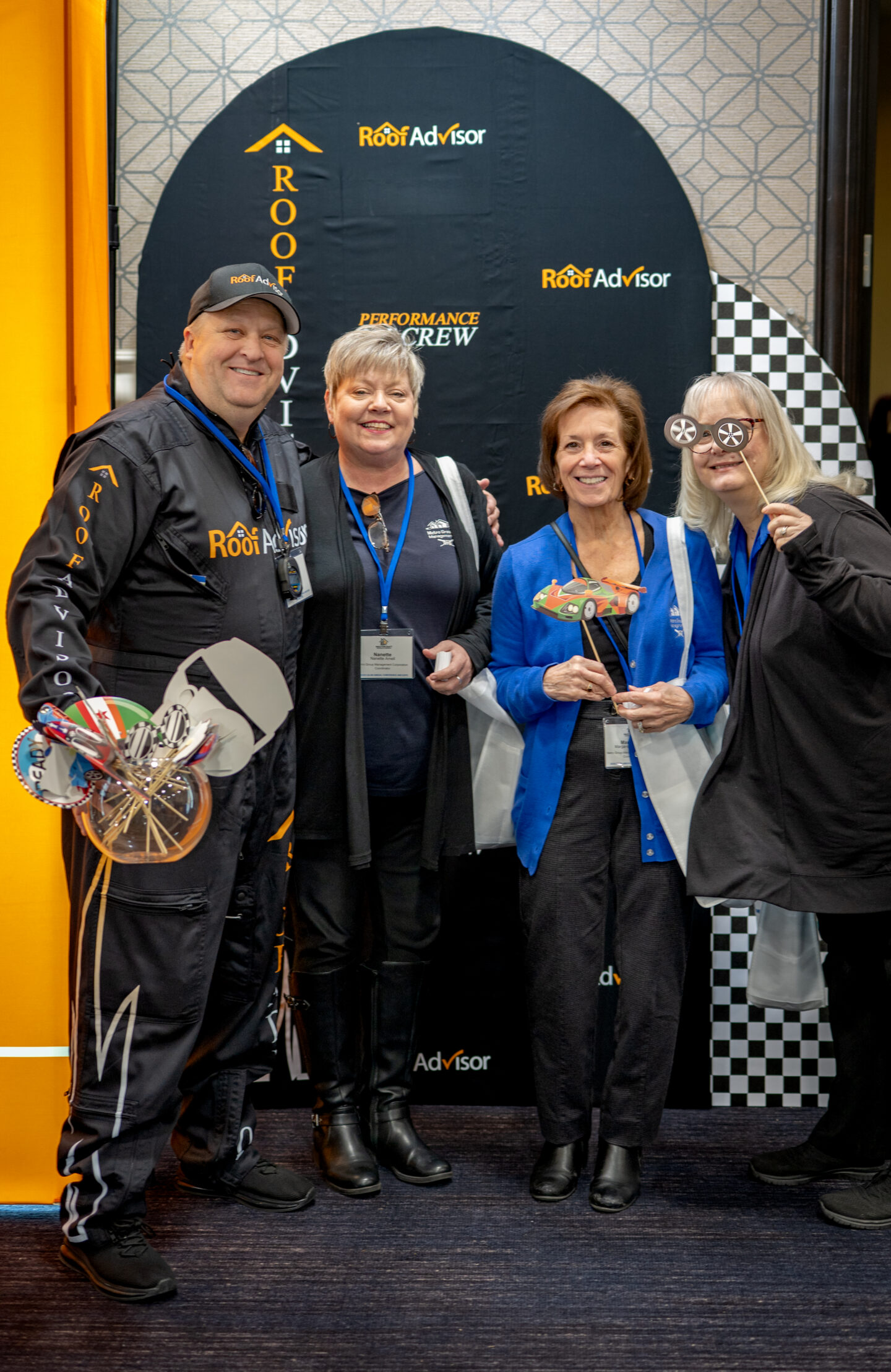 Roof Advisor's Performance Crew poses in front of the Roof Advisor backdrop, CAI202605.jpg. The crew is smiling and holding fun props for the photo op.