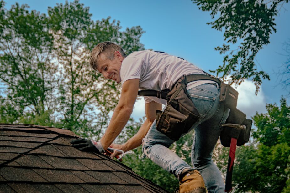 Roof health check. Roofer inspecting roof shingles for leaks. No-leak guarantee for 1-year.