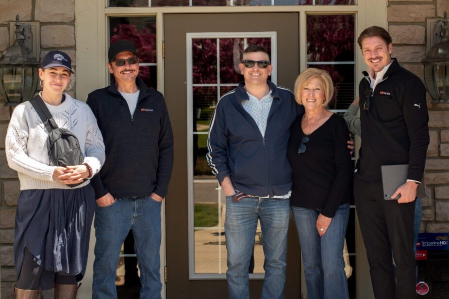 Michigan multi-family roofing team. Group photo of board members and property manager in front of building.