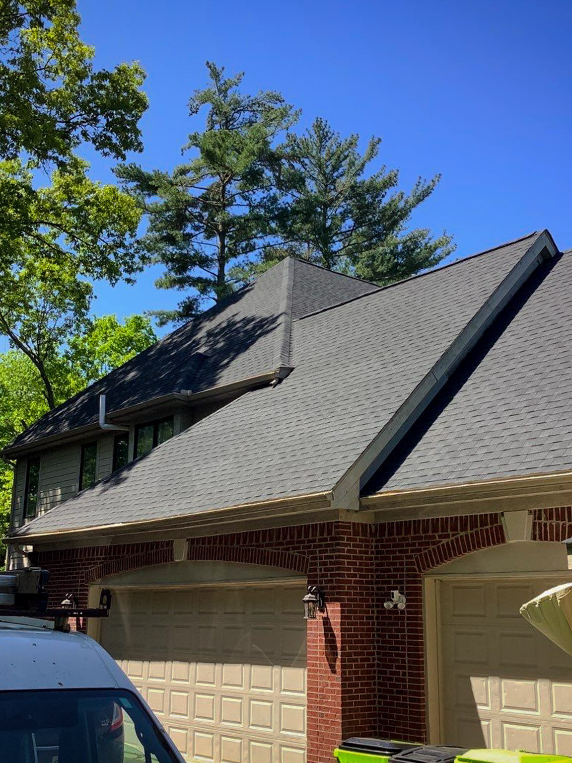 Milford Hill Hollow house with a Roof Advisor van for roof replacement. The unique roof design is surrounded by trees.