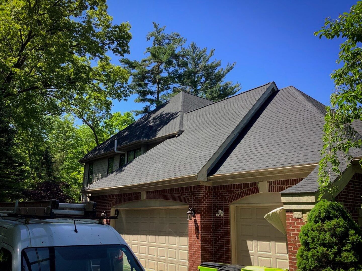 Milford Hill Hollow house with a Roof Advisor van for roof replacement. The unique roof design is surrounded by trees.