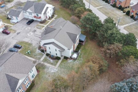 Aerial view of the Stonegate Clinton residential complex showing multi-family townhouse units, paved parking areas, and surrounding green space with trees