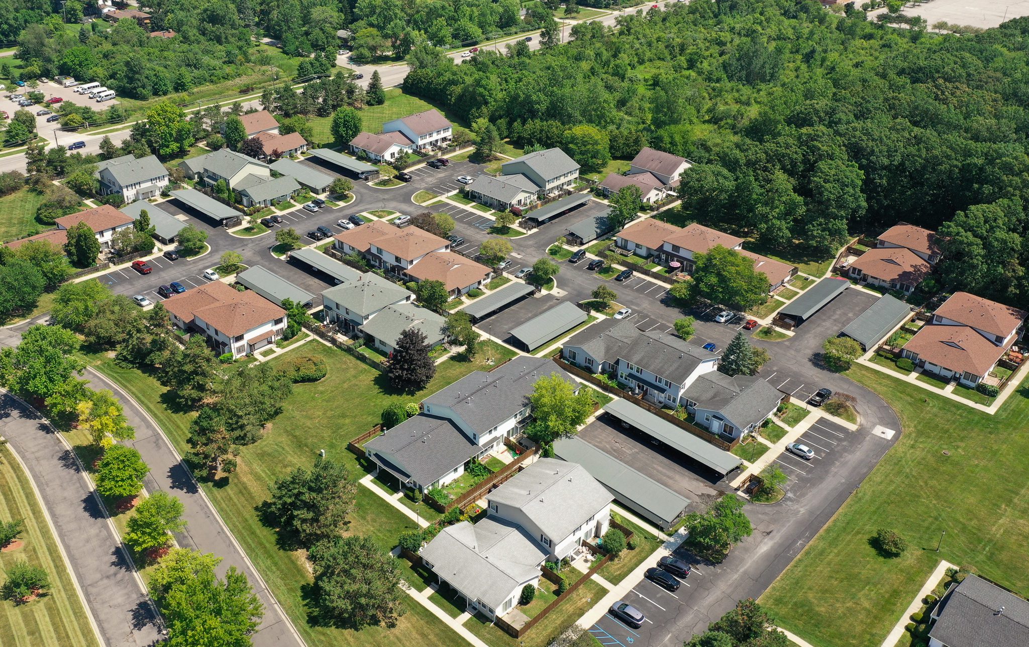 Top-down angled view of Roundtree community projects, featuring homes, parking, and green spaces. Lush trees surround the neighborhood.