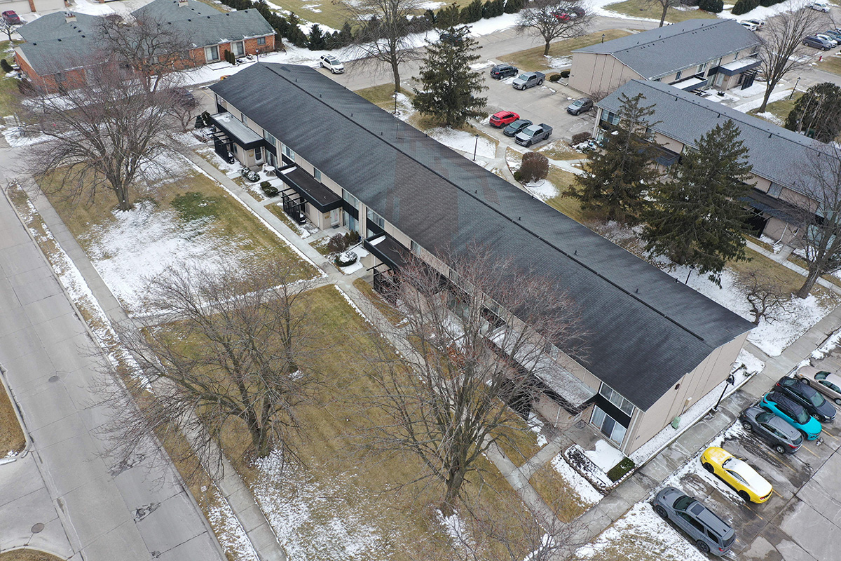 Warren MI City Center building before renovation, part of current community projects. Aerial view of apartment complex with cars and light snow.