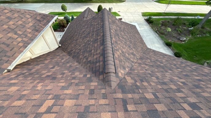 Aerial view of a shingle-covered residential roof with multiple intersecting slopes and ridge caps