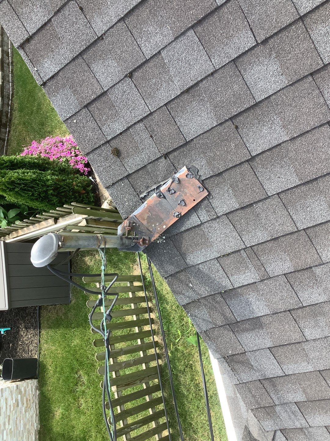 Overhead view of a Dearborn roof showing aged shingles and a metal flashing base with dark sealant around a vent pipe before a planned repair project.