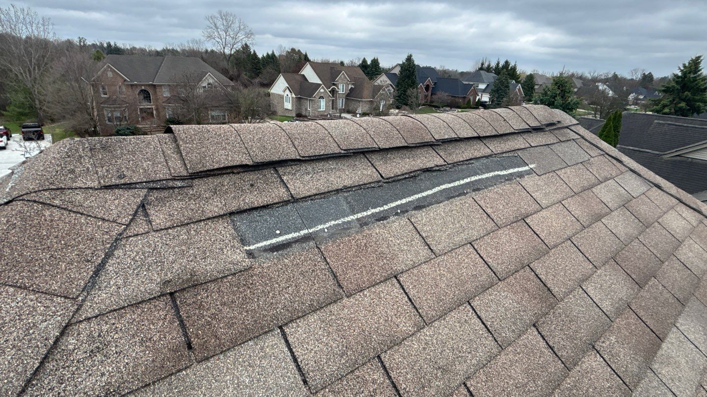 Close up of a damaged shingle roof in Plymouth MI showing a specific section with missing material and a white chalk line marking area for replacement.