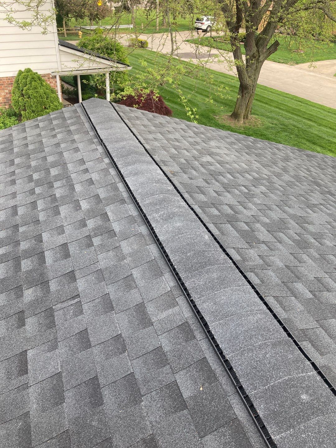 Andrea M's 5-Star Roofing in Clinton Township: A close-up of the newly installed gray asphalt shingle roof, showcasing the roof's ridge vent for ventilation.