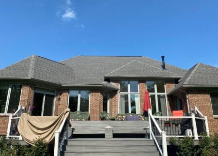 New Baltimore roof replacement: Close-up of a home's backyard featuring a new, gray roof. The roof is clean and well-installed, enhancing the home's value.