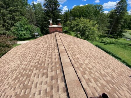 Newly replaced roof in Ann Arbor. The image showcases the completed roof replacement on Bill's home, featuring GAF Shakewood asphalt shingles and a chimney.