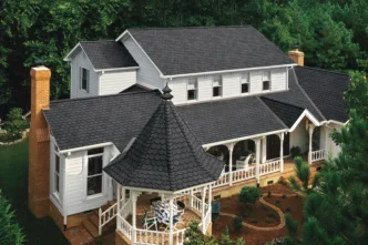 Carriage House by CertainTeed in Black Pearl: A beautiful home featuring a distinctive black roof with a gazebo, surrounded by lush greenery.
