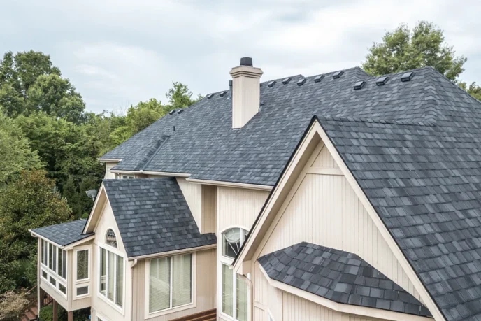 Belmont IR roofing shingle options MI: A house featuring a dark gray asphalt shingle roof, showing texture and design against a lush backdrop. Upgrade existing attic vents. Get the same wind resistance classifications and fire rating of other designer shingles.