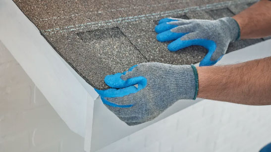 Integrity roof: Installing the starter shingle. Hands in gloves carefully position a starter shingle, ensuring proper alignment for a durable roof. 