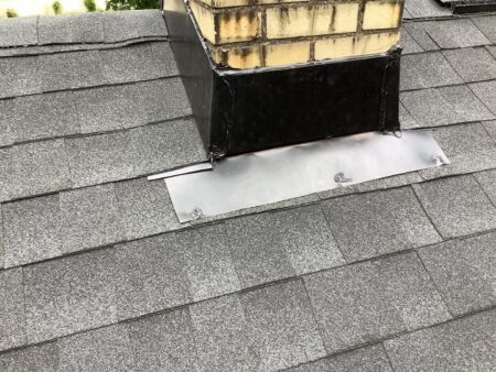 Westland roof replacement: Chimney flashing repair, showcasing new, secure flashing around the chimney base after replacement for optimal protection.