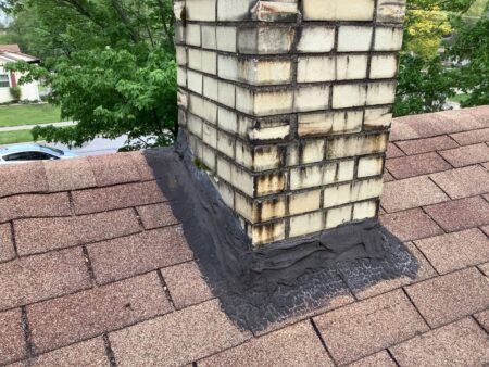 Before image of a Westland roof replacement showing deteriorated chimney flashing. Damaged flashing needs repair to prevent leaks. Roof repair needed.