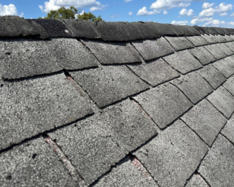 RoofAdvisor Gallery: Close-up of curling, worn ridge cap shingles. Weathered roof with damaged asphalt shingles needing replacement. Roofing repair needed.