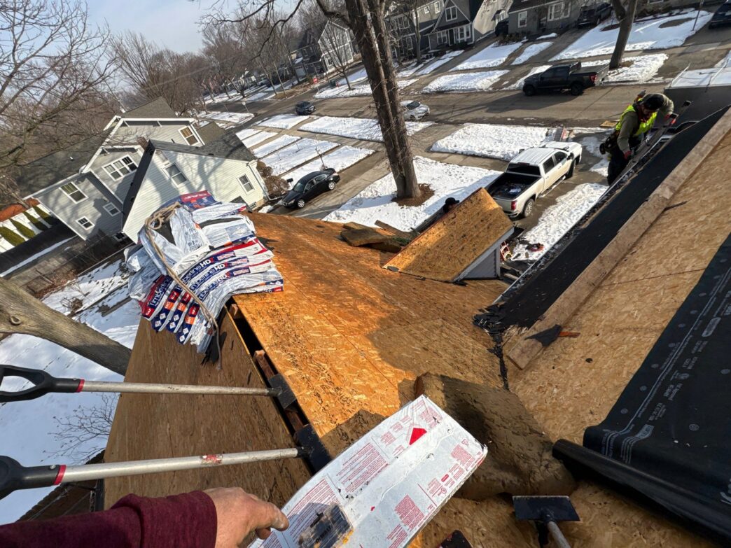 Dan Oshea 5-Star Roofing: Royal Oak roof replacement process. Shows roofers working on a pitched roof with materials. Roof repair in progress.