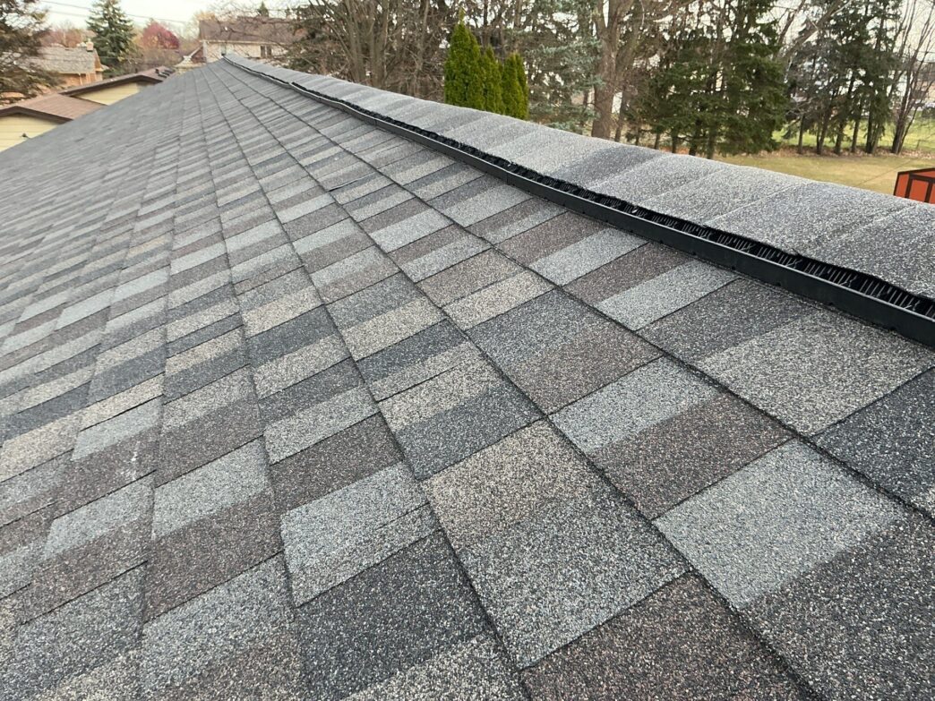 Sterling Heights roof with new gray asphalt shingles and a black ridge vent installed along the peak, providing ventilation for roof replacement project.