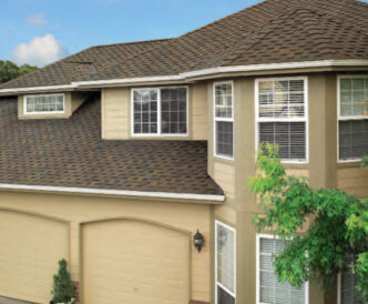 GAF Designer Grand Sequoia Autumn Brown. Example roof on a tan house with a two car garage and white trim. Architectural asphalt shingles.