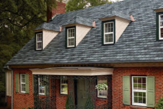 Designer roofing system GAF Slateline roofing example in English Gray on a brick house. The roof has dormer windows and copper accents.