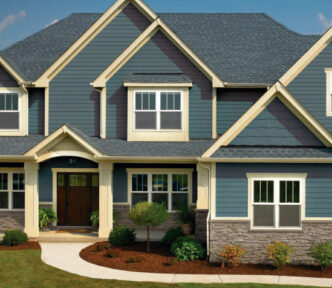 GAF Timberline ArmorShield II example roof in Pewter Gray. Architectural asphalt shingle roofing on a house with blue siding and stone veneer.