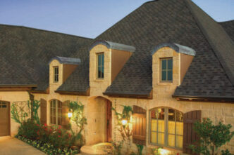 GAF Timberline roofing system Grand Sequoia Designer roof. Example of a home with grand sequoia shingles, stone facade, dormer windows, and professional landscaping.