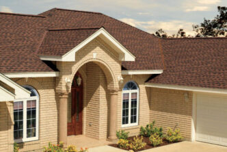 GAF Timberline roofing system HDZ in Hickory. Example roof on a brick home with an arched entryway, columns, and a two-car garage. Landscaped front yard.