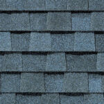 Close-up of CertainTeed Landmark Pro Max Def Coastal Blue shingles. Roofing material with a grainy texture and a uniform staggered pattern. Durable roofing.