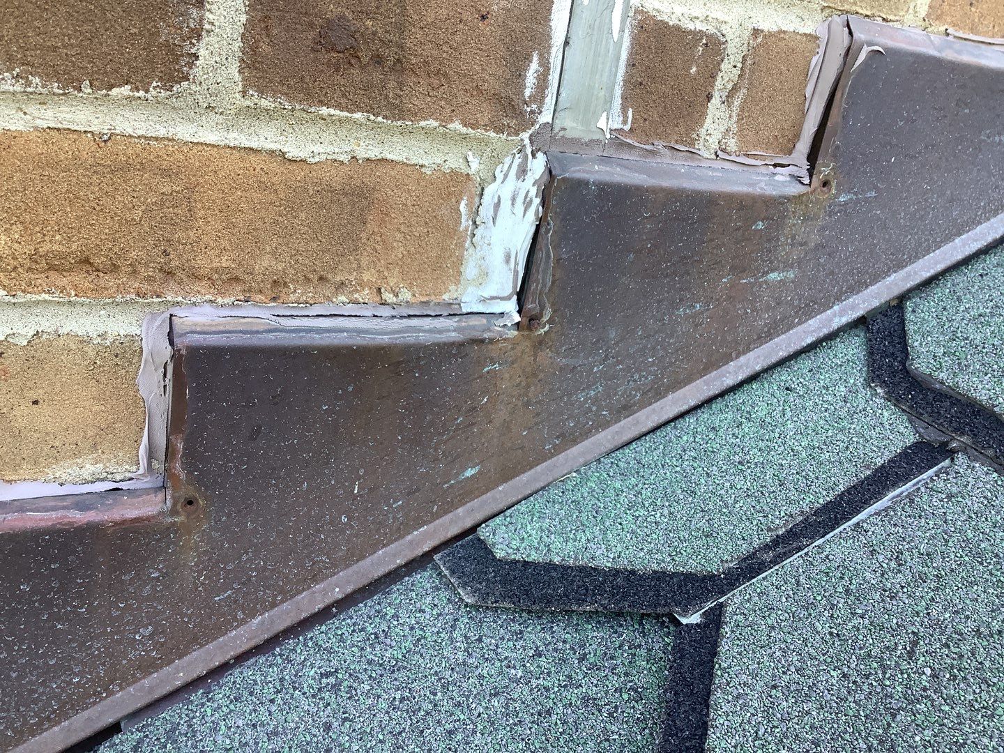 The step flashing on the chimney of Lori's Plymouth home before roof repair.