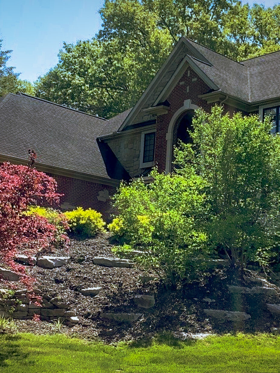 Milford Hill Hollow roof replacement. A house with a unique roof design is surrounded by trees. The front of the home is visible.