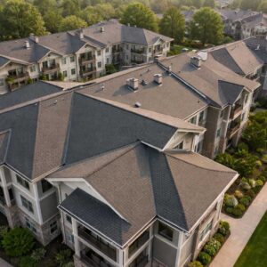 Aerial view of apartment buildings with dark gray roofs shows roofing quality & design for property managers.