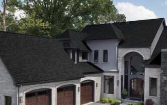 Owens Corning Duration Onyx Black Shingles on a luxury home. The dark roofing complements the light brick and gray facade, enhancing curb appeal. 