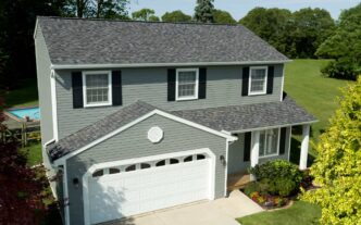 Owens Corning Duration Williamsburg Gray shingles on a two-story house. Durable roofing with a classic aesthetic, enhancing curb appeal and protection.