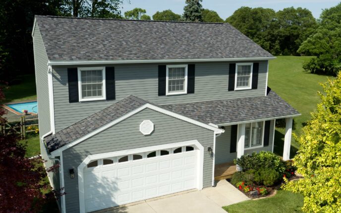 Owens Corning Duration Williamsburg Gray shingles on a two-story house. Durable roofing with a classic aesthetic, enhancing curb appeal and protection.