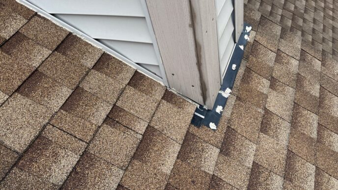 Damaged flashing on a Plymouth roof before repair by 5-Star Roofing's Paul M. shows signs of wear and potential leaks. Brown shingles meet siding, needing attention.