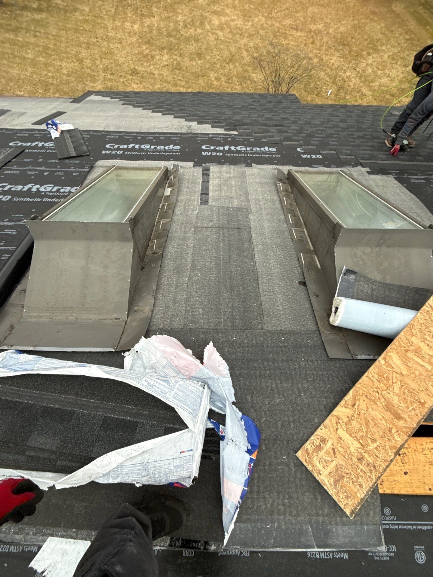 Roof installation in progress showing two rectangular roof vents, underlayment, and partially installed shingles.