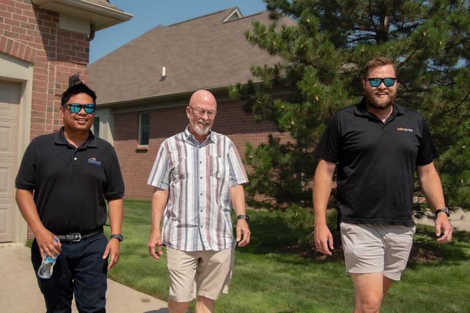 Roof Health Check: Three men walk in front of a house. Property management maintenance plan includes regular inspections.