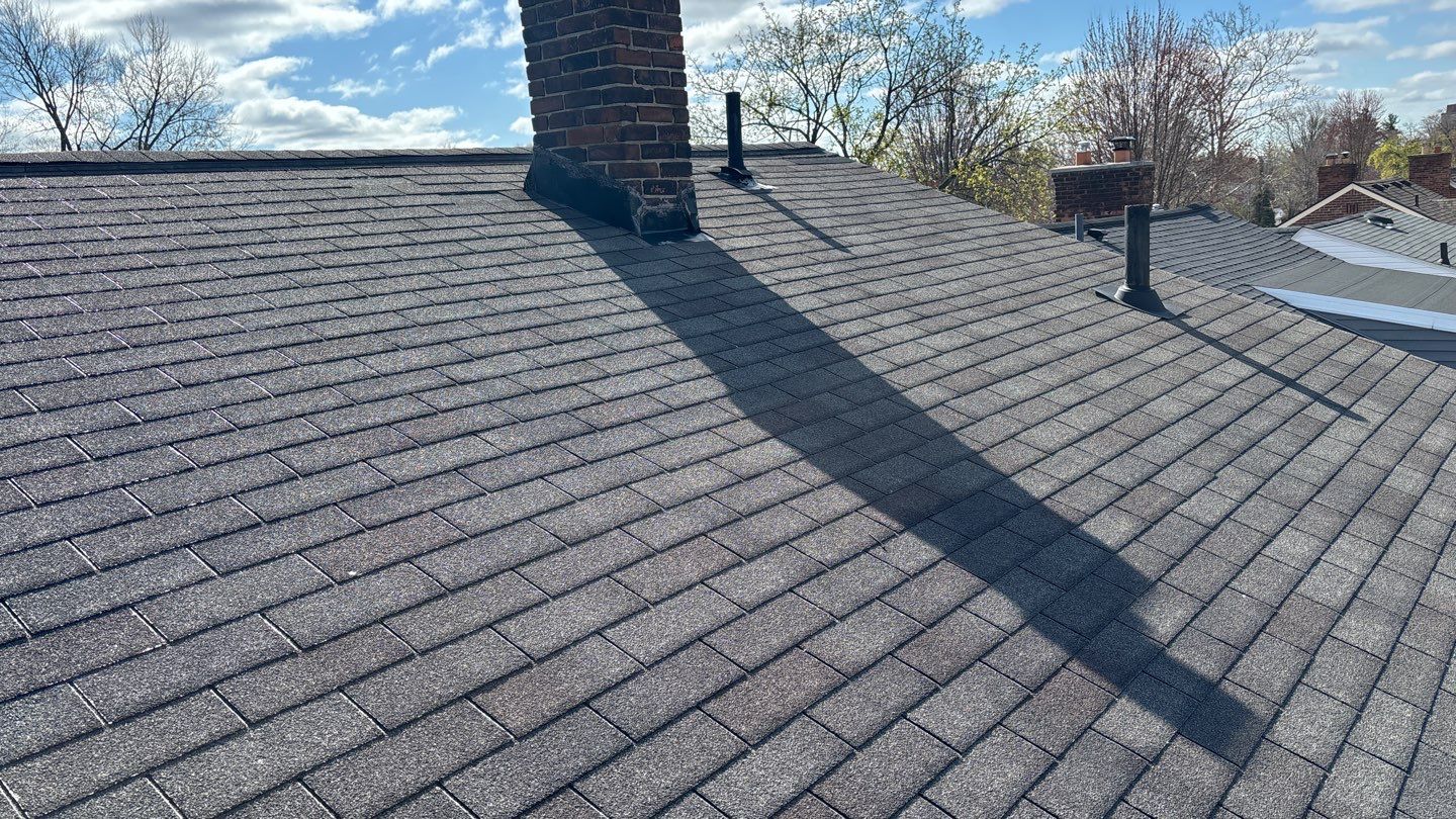 Dearborn roofing with dark asphalt shingles and a brick chimney before a GAF Timberline HDZ replacement project takes place.