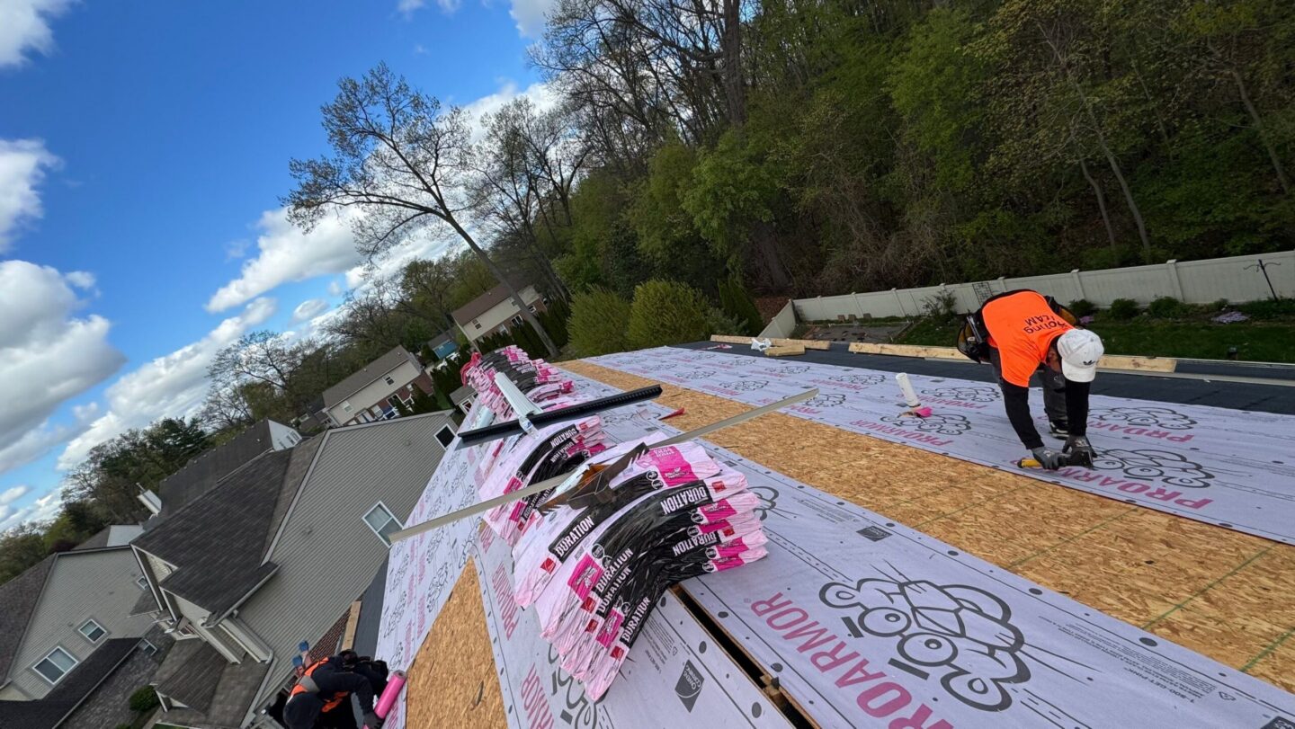 Roofers installing underlayment on a steep house roof. Robert K Roofing Process in Westland, MI