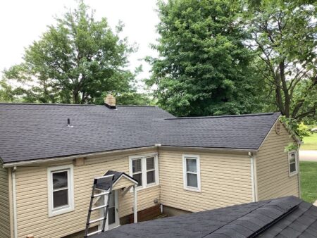 Westland Roof Replacement: A full view of the newly replaced dark gray roof on a beige house with green trees in the background. Shows roof after completion.