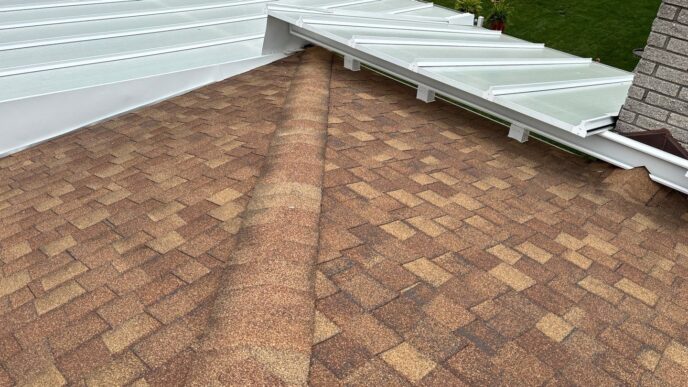 Brown architectural shingle roof beneath white patio cover with visible ridge cap detail