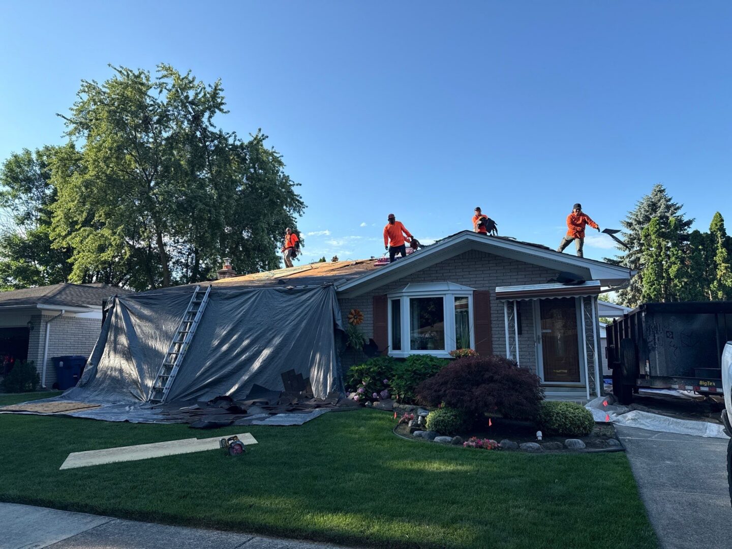 Workers working on roof with tarps laid out protecting the property