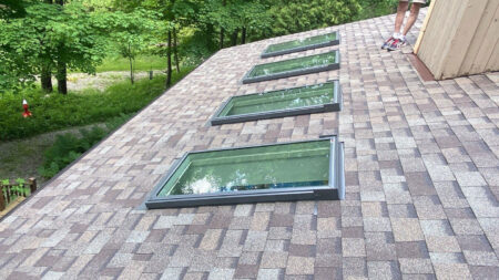 After Canton roof replacement by Bruce's, showing new skylights installed on a brown shingled roof, enhancing natural light and ventilation in the home.